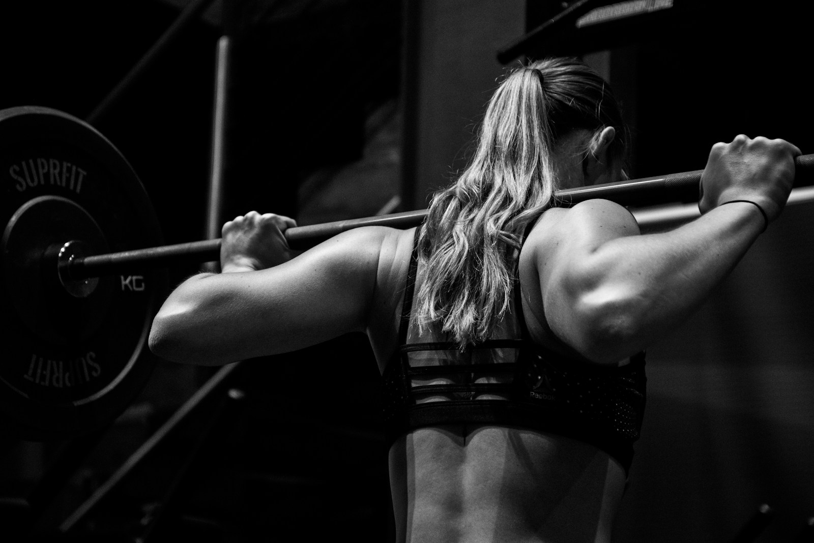Przysiad do skrzyni – zalety, technika i unikanie kontuzji woman lifting barbell